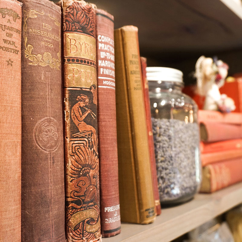 vintage books on a shelf with a jar of lavender buds